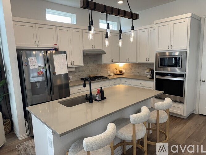 A kitchen with white cabinets and a large island with bar stools.