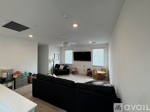 A living room with a black couch and a television.