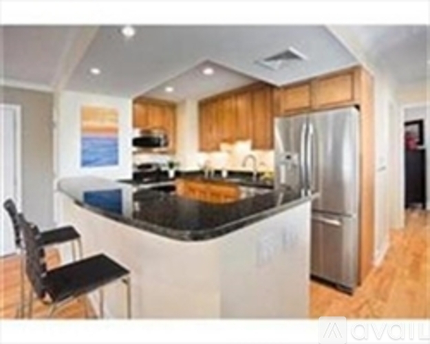 A kitchen with a black counter top and wooden cabinets.