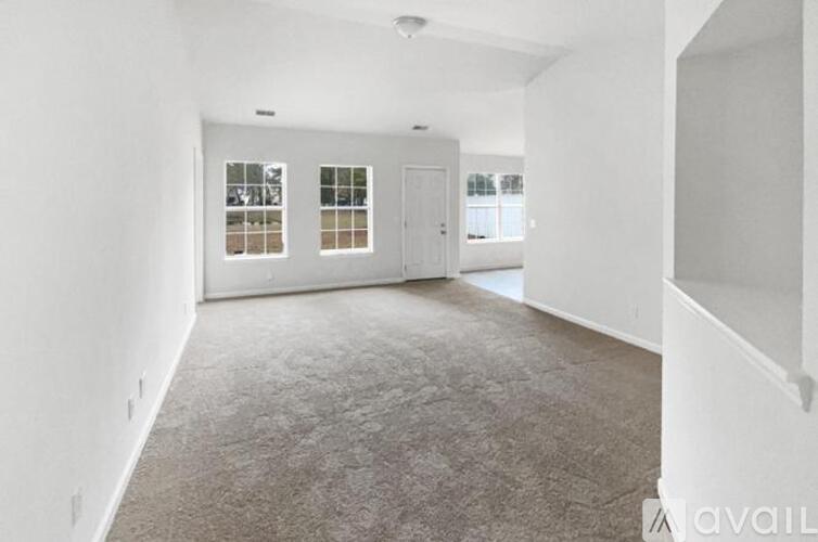 A spacious room with carpeted floor and two windows.