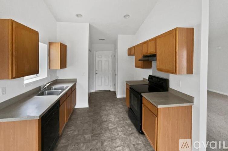 A kitchen with wooden cabinets and a black dishwasher.
