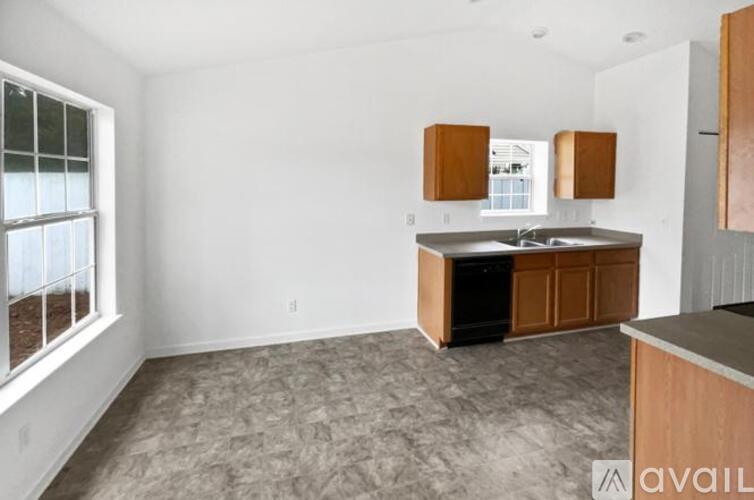 A kitchen area with a sink, cabinets, and a window.