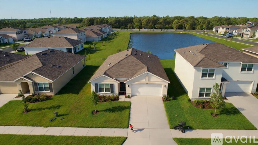 A bird's eye view of a suburban neighborhood with houses and a lake.