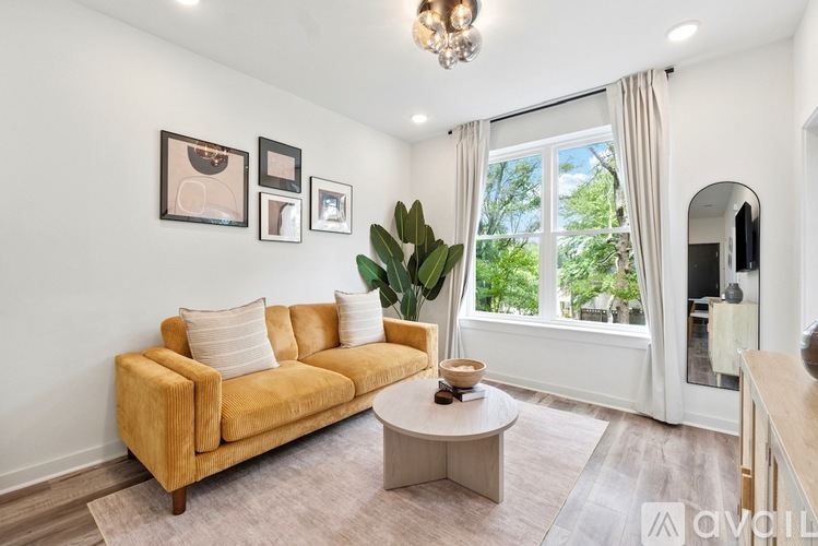 A living room with a yellow couch, a coffee table, and a chandelier.