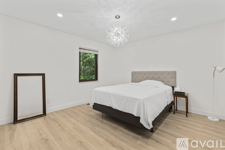 A bedroom with a large bed, a chandelier, and a window with a view of trees.
