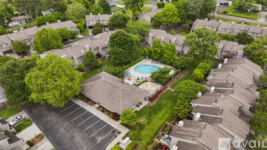 A bird's eye view of a residential area with houses, a swimming pool, and a parking lot.