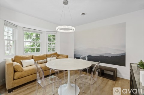 A modern living room with a large couch, a table, and a painting on the wall.