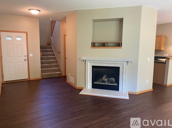 A living room with a fireplace and a staircase.