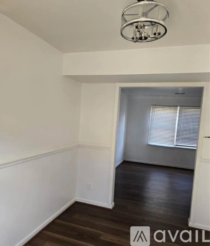 A room with a wooden floor and a white wall with a window.