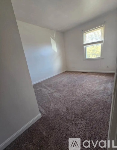 A room with a carpeted floor and a window.