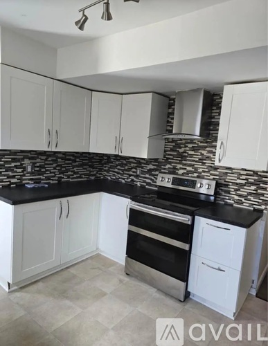 A kitchen with white cabinets and a black countertop.
