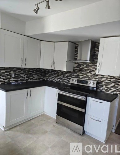 A kitchen with white cabinets and a black countertop.