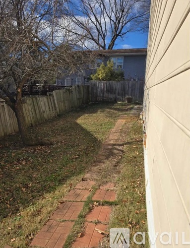 A backyard with a brick walkway and a wooden fence.