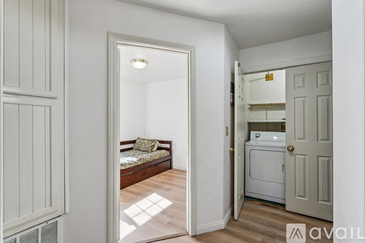 A small bedroom with a bed and a washing machine in the corner.
