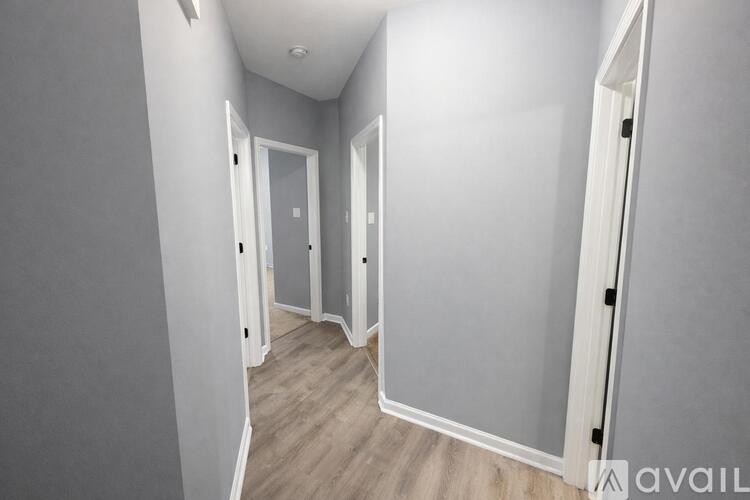A hallway with white doors and a wooden floor.