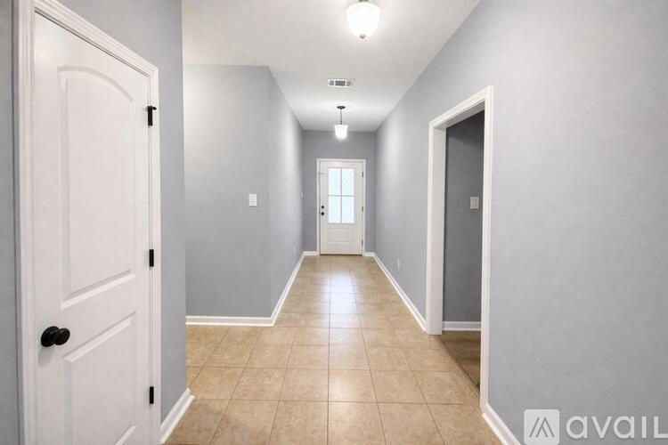 A long hallway with a white door on the left and a light on the ceiling.