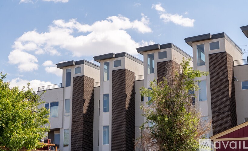 A row of modern apartment buildings with balconies and trees in front.
