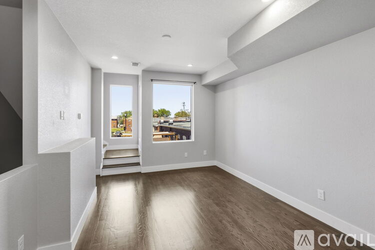 A spacious room with wooden floors and a view of the outdoors through a large window.