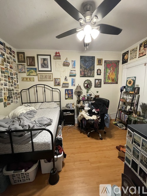 A bedroom with a bed, a chair, and a wall covered in pictures and posters.