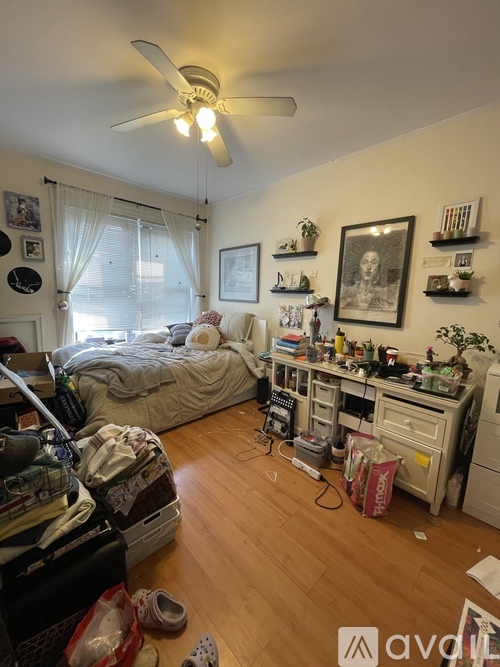 A messy bedroom with a bed, desk, and various items scattered about.