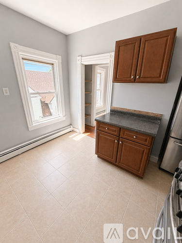 A kitchen with a window, a fridge, and cabinets.