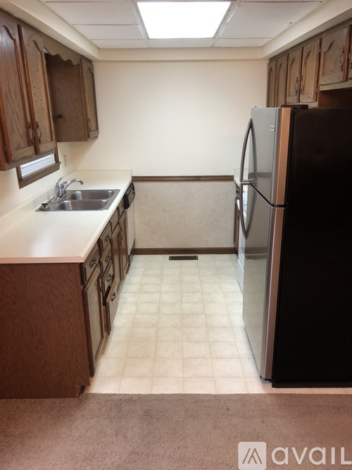 A kitchen with a sink, refrigerator, and cabinets.