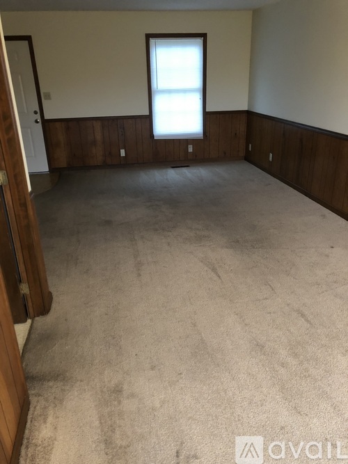 A room with a carpeted floor and a window.