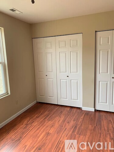 A room with two white doors and wooden flooring.