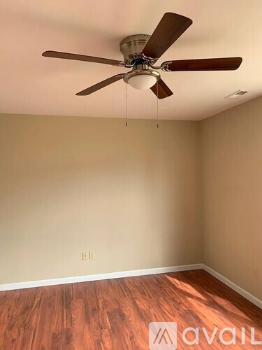 A room with a ceiling fan and wooden flooring.