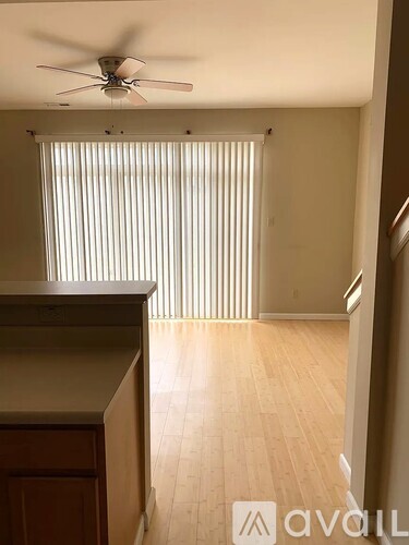 A room with a ceiling fan and wooden flooring.