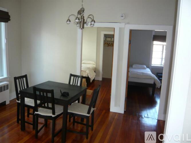 A black dining table with four chairs is in a room with white walls.