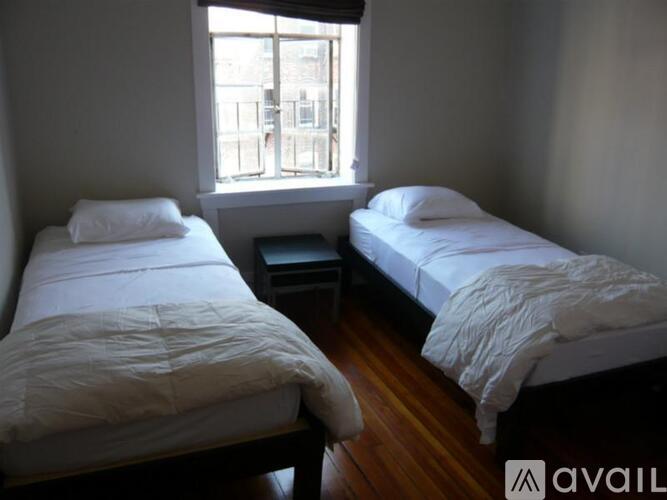 Two beds with white bedding in a room with wooden floors and a window.