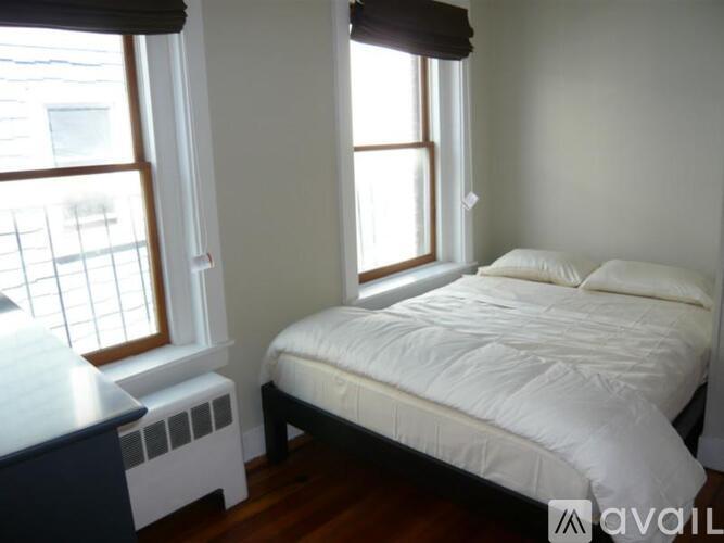 A bedroom with a bed, nightstand, and window.