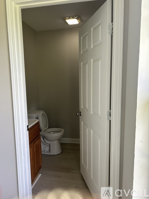 A white door is open to a bathroom with a toilet.