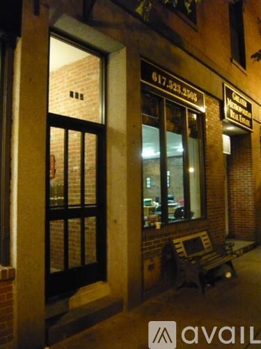 A bench is outside of a building with a window that has a sign on it.