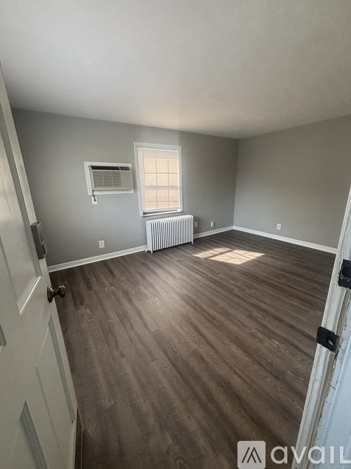 A room with wooden flooring and a window with blinds.