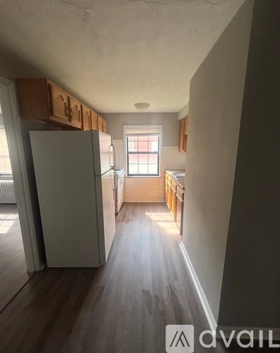 A kitchen with a white refrigerator and wooden cabinets.