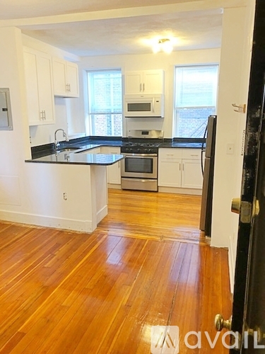 A kitchen with white cabinets and black countertops.