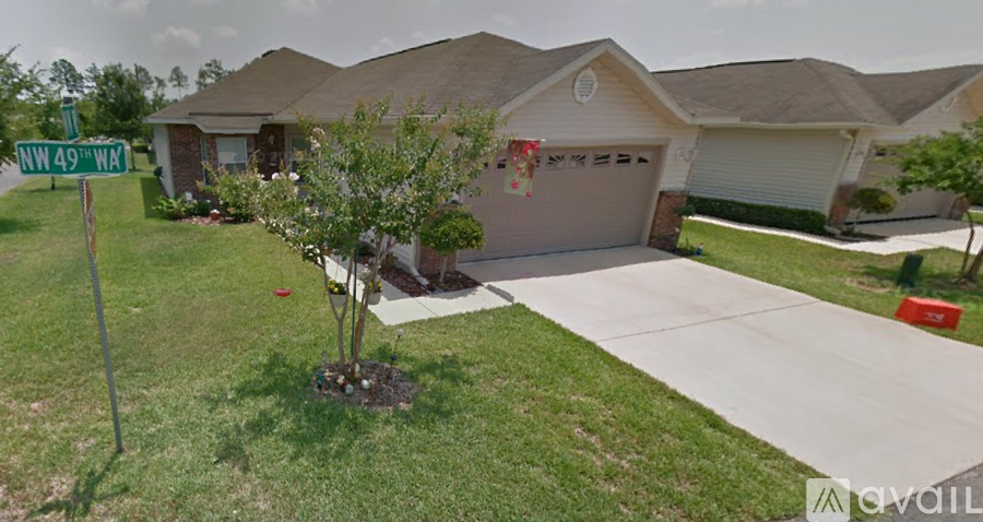 A tree in a pot is in front of a house with a sign that says NW 49 WA.