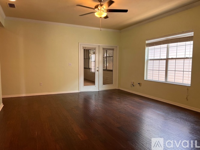A room with a ceiling fan and a door leading to another room.