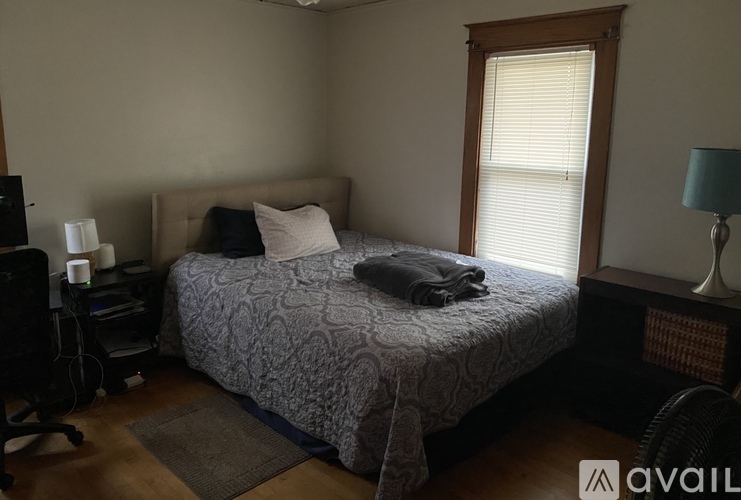 A bedroom with a bed, a chair, and a lamp.