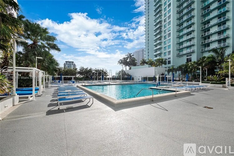 A large outdoor swimming pool surrounded by lounge chairs and palm trees.