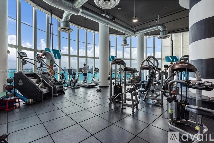 A gym with a variety of equipment and a large window overlooking the water.