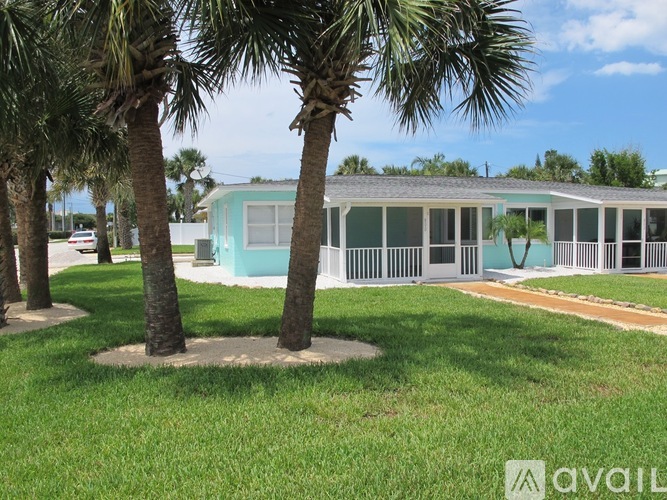 A house with a blue roof is surrounded by palm trees.