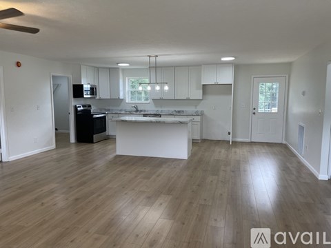 A spacious kitchen with white cabinets and a wooden floor.