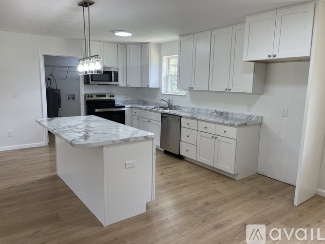 A kitchen with white cabinets and a marble island.