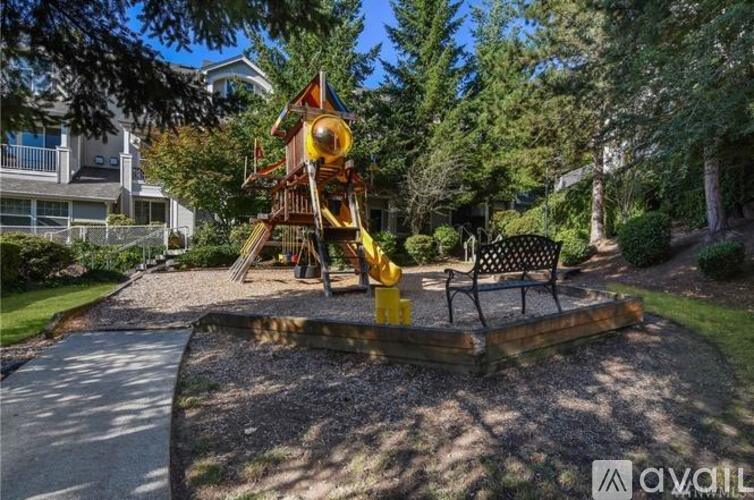 A playground with a yellow slide and a black bench.