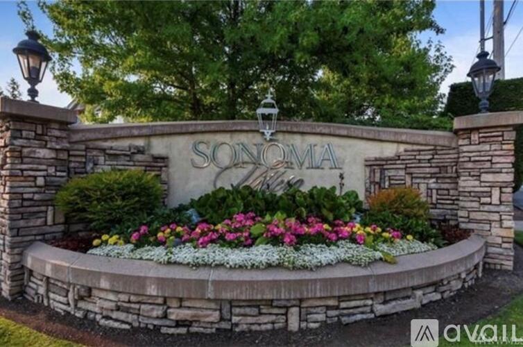 A stone wall with a sign that says Sonoma and flowers in front.