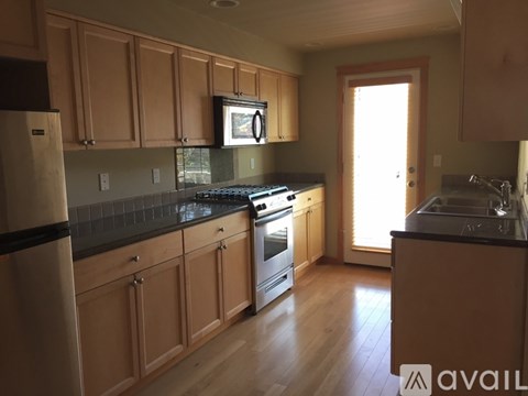 A kitchen with wooden cabinets and black countertops.