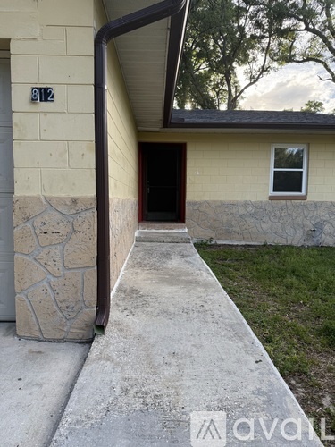 A yellow house with a stone pillar and a black door.